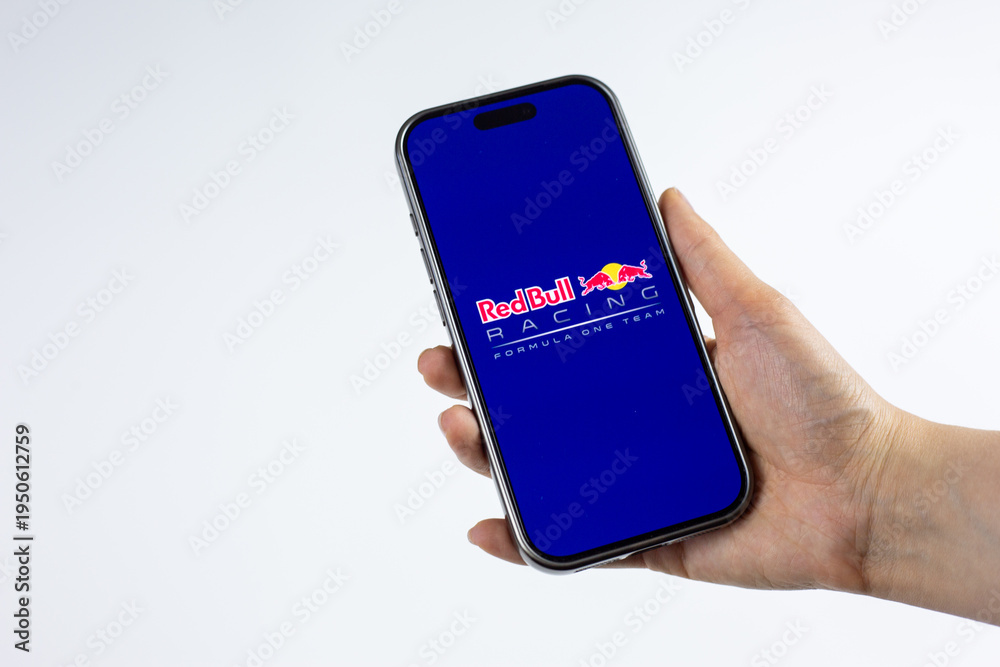Fototapeta premium Moscow, Russia, March 14, 2026: Smartphone in hand showing Red Bull Racing Formula 1 Team logo on display, isolated on white background. Team spirit, racing heritage and podium ambitions in F1