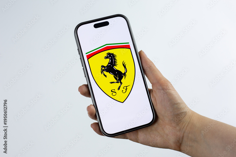 Obraz premium Moscow, Russia, March 14, 2026: Smartphone in hand showing Scuderia Ferrari shield logo with prancing horse on display, isolated. Formula 1 victories, podium finishes and championship spirit in race