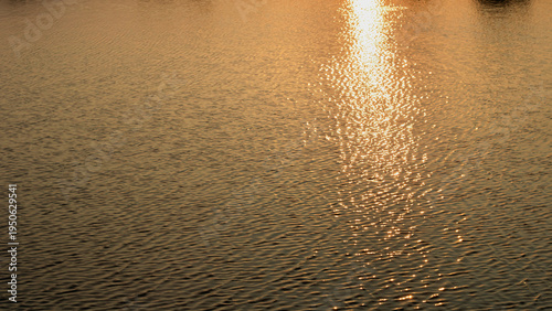 Foto Golden sunlight reflecting on rippled water surface creating shimmering light pattern, natural abstract background with warm tones and peaceful atmosphere