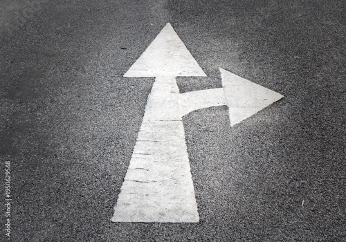 White straight and right turn arrow road marking painted on asphalt street surface, traffic direction symbol used for transportation guidance and navigation.
