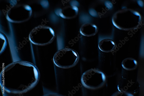 A cluster of black impact sockets is captured from a top-down perspective, with the central row in sharp, crisp focus to showcase the precision-engineered hexagonal heads. 