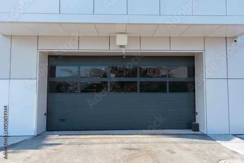 Modern commercial garage door with large glass panels and sleek design, situated in a contemporary building with clean lines and minimalistic architecture