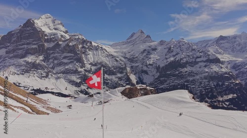 Cinematic shot of the Swiss flag with the Eiger, Monch, and Jungfrau peaks in background.
