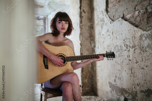Young Woman Playing Acoustic Guitar in Abandoned Interior