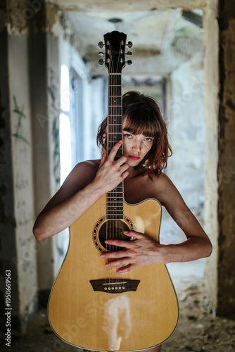 Sensual Female Musician Holding Acoustic Guitar in Abandoned Interior