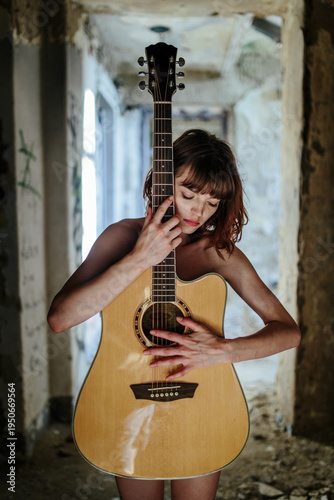 Sensual Female Musician Holding Acoustic Guitar in Abandoned Interior