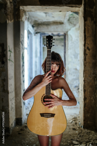 Sensual Female Musician Holding Acoustic Guitar in Abandoned Interior
