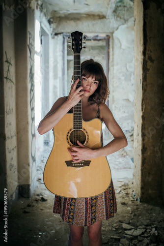 Sensual Female Musician Holding Acoustic Guitar in Abandoned Interior