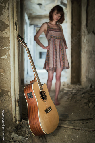 Acoustic Guitar in Abandoned Interior with Woman in Background