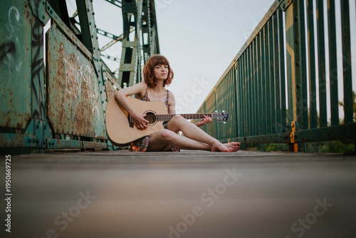 Young Woman Playing Acoustic Guitar on Urban Bridge