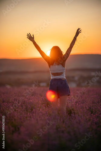 Lavender field woman raising arms celebrating freedom during golden sunset