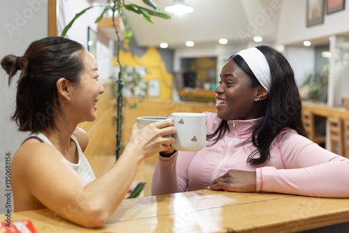 Obraz na płótnie Empowerment and friendship shine in a climbing gym as two women enjoy their coff