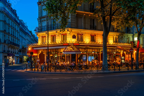 Cozy street with tables of cafe in Paris, France. Night cityscape of Paris. A...