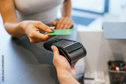 Customer performing a secure financial transaction using a green contactless credit card and portable pos terminal