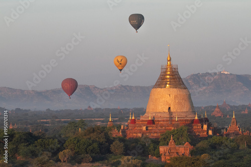 Hot air balloons float close to a large pagoda under renovation at Bagan.