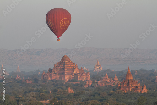 A hot air balloon floats above the many pagodas in Bagan at sunrise.