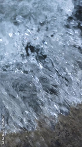 Small urban drainage ditch waterfall with stormwater flowing rapidly over concrete and stones.