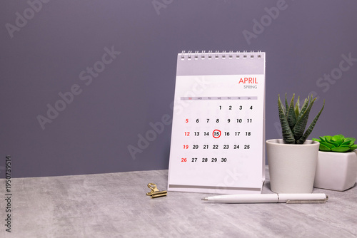 A wooden calendar with the date April 15 on the desktop.