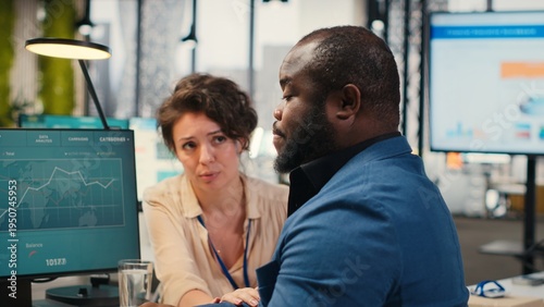 Obraz na plátně Exasperated black manager dealing with a stressful situation at the office, worried stressed woman colleague trying to calm him down and showing empathy