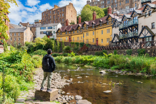 A man is enjoying beautiful view at Dean Village, Edinburg, Scotland. A picturesque, tranquil oasis, formerly an industrial milling hub for over 800 years, now features quaint 19th-century stone house