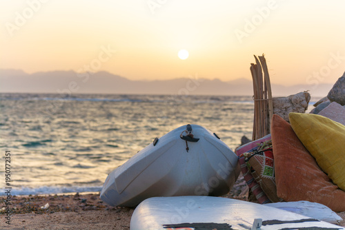 Bild auf Leinwand Inflatable Boat and Surfboard on a Beach at Sunrise