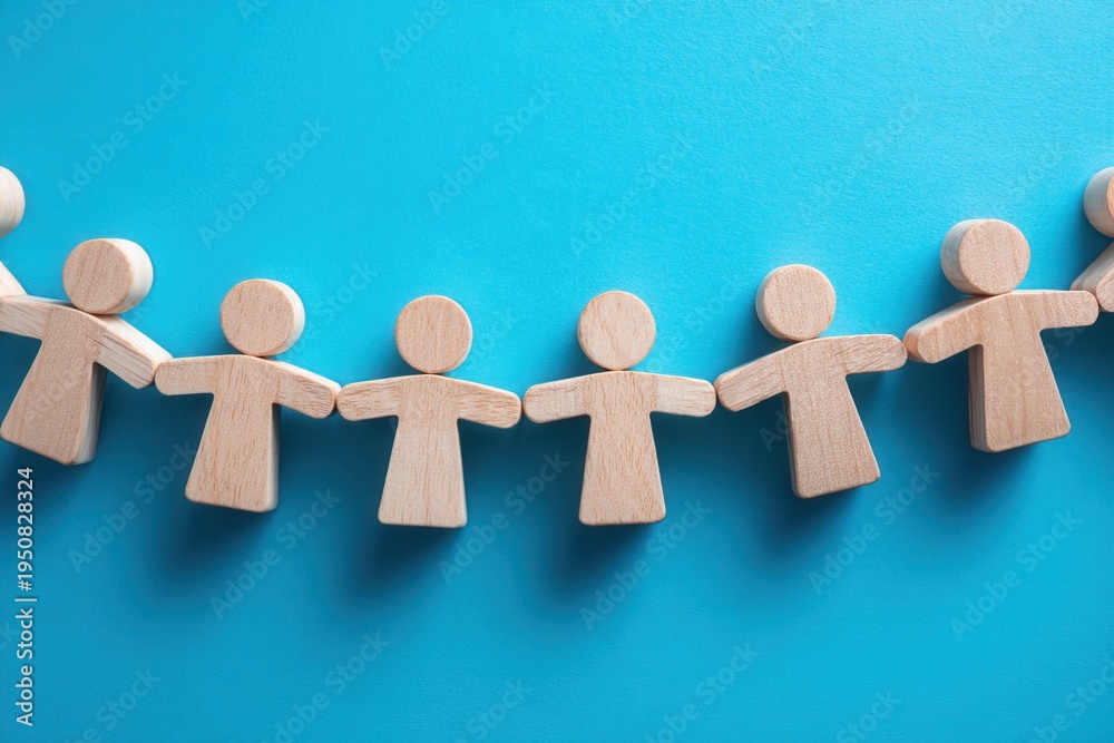 Obraz premium Interconnectedness in Community: Wooden figures hold hands in a chain, symbolizing community, unity, and the bonds that connect individuals together on a vibrant blue background.