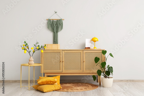 Interior of stylish room with commode, table and lemon tree branches