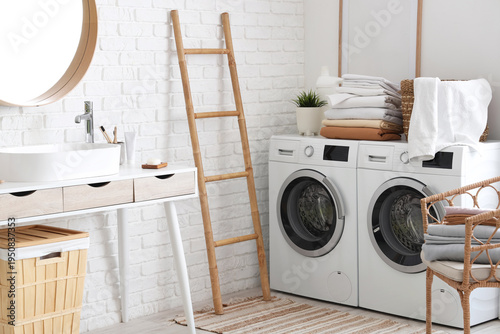 Interior of laundry room with washing machines, ladder and clean bed sheets