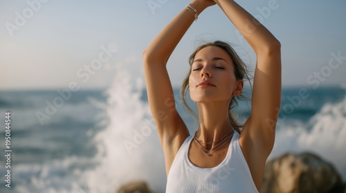 Young woman practicing yoga and meditation on a rocky beach with splashing waves.