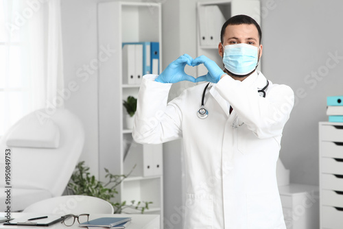 Young male doctor with protective mask and stethoscope showing heart gesture ...