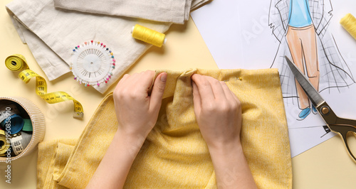 Female hands sewing yellow ...
