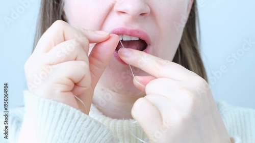 Young woman brushing her teeth with dental floss close-up front view.
