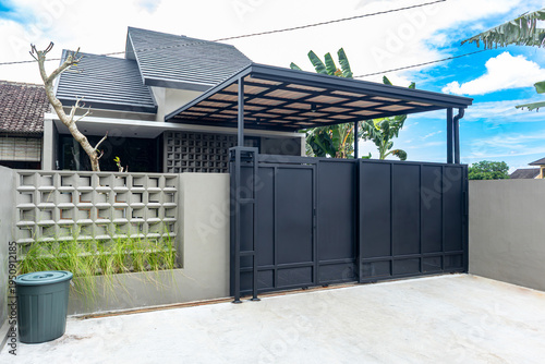 Asian simple minimalist modern tropical house with big bold black iron plate fence and uPVC canopy