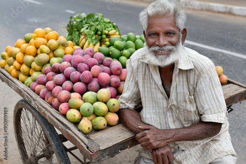 Indian fruit seller with a rustic cart full of fresh seasonal fruits on local market