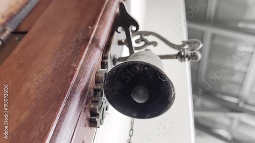A unique low-angle shot of a vintage bell, emphasizing its size and the craftsmanship of the wooden mounting.