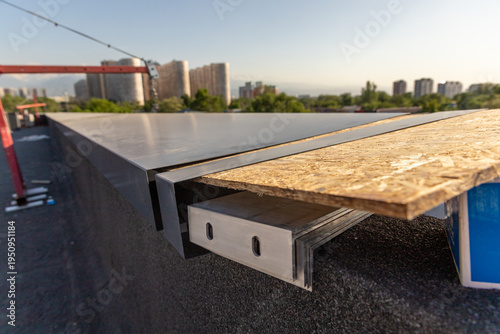 Billede på lærred Close-up of metal flashing and OSB board assembly for cornice installation on a flat roof edge during finishing