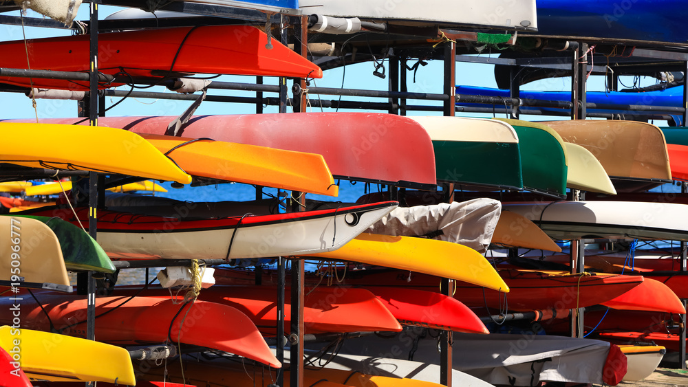 Naklejka premium Kayaks and canoes stored on a rack near water