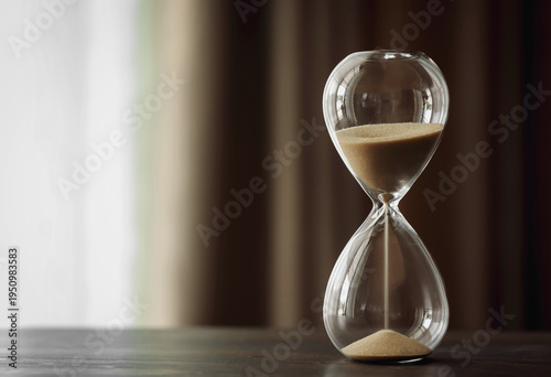 Obraz na plátne An hourglass sits on a wooden table