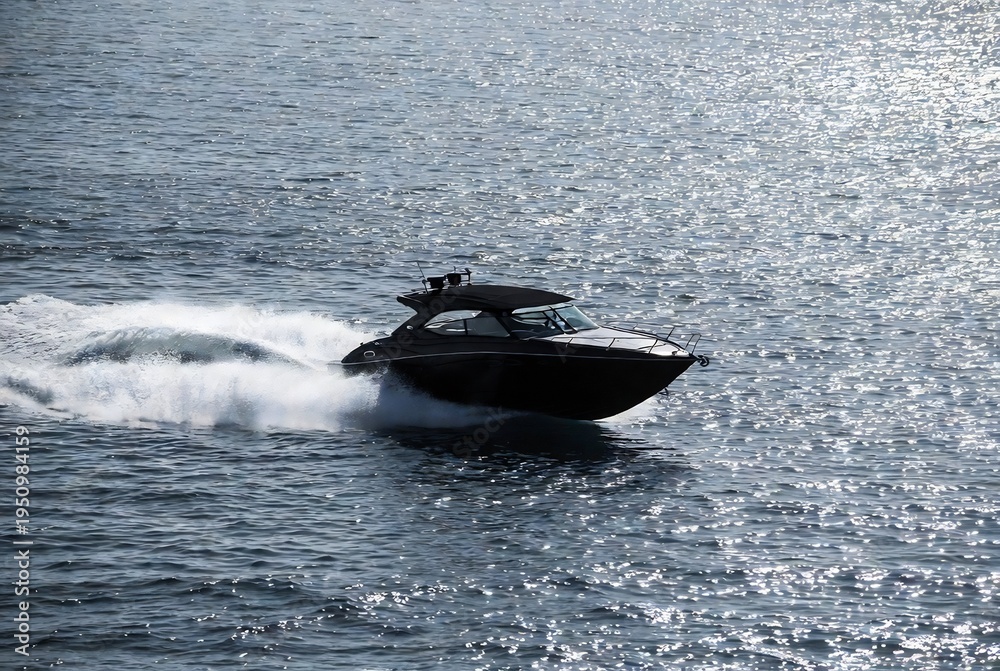 Fototapeta premium A speedboat is moving across the water. It’s a calm, blue ocean scene.