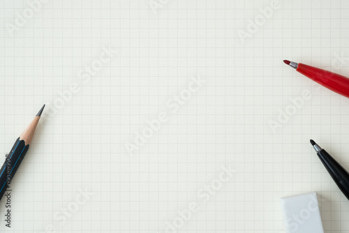 Top view, Close-up of Red and Black Felt-tip Pen, Pencil and Eraser on Graph Paper Background, Copy Space for Text, Flat Lay Concept.