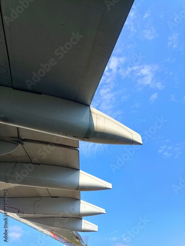 Close-up photo of an aircraft wing taken from below with the canoe fairing and slats under bright blue sky