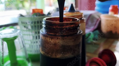 Soy sauce is being poured into a plastic bottle. 