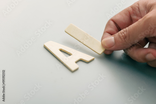 Hand arranging wooden AI letters on clean background