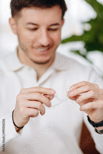 Man holding clear dental aligners with smile preparing to insert invisible retainer
