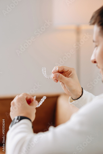 Man holding clear dental aligners at home preparing to insert invisible orthodontic trays