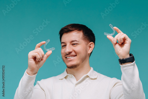 Smiling man comparing clear dental aligners for orthodontic treatment and at-home teeth straightening