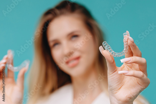 Woman holding clear aligners for dental orthodontic treatment and smile care in studio portrait