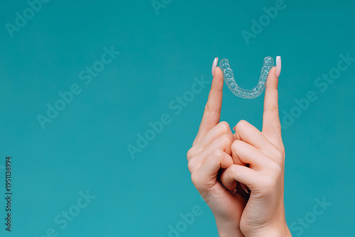 Hands holding a clear dental aligner retainer for orthodontic teeth straightening and cosmetic dentistry