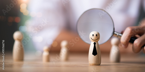 Foto A magnifying glass focuses on a wooden figure with a smile and tie, symbolizing talent selection, recruitment, candidate evaluation, the search for the perfect employee in human resource management