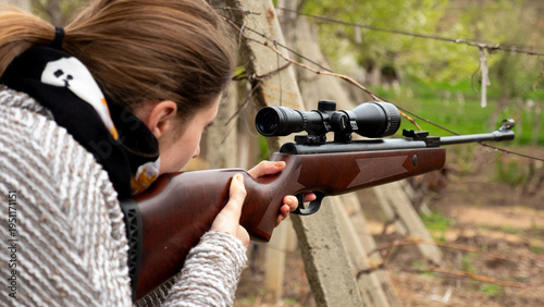 Принти на полотні A woman focuses on her target while holding a rifle at an outdoor shooting range